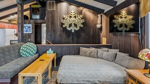 A cozy interior with a sofa, a wooden table, and a wall-mounted sign reading 'MAD RIVER GLEN'.