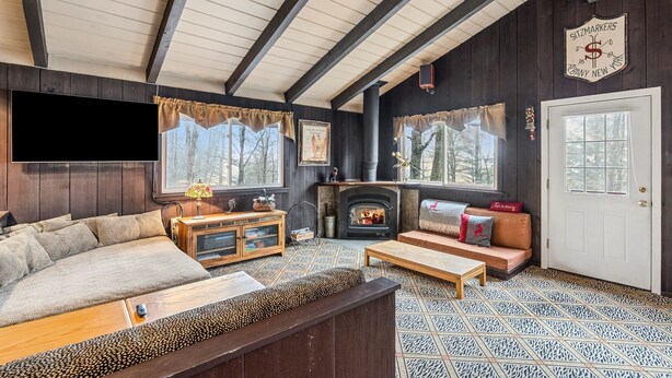 A cozy living room with a fireplace, wooden beams, a sofa, and a television.