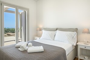 Una camera d'albergo con un letto, due comodini, vista attraverso una porta scorrevole e una lampada su ogni comodino.