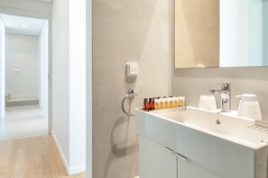 Un bagno moderno con lavandino, specchio e articoli da toilette bianchi.
