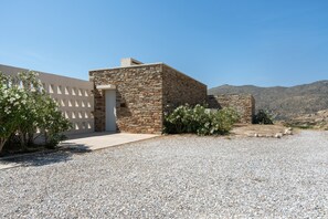 Un edificio con facciata in pietra, una porta bianca e un vialetto sterrato.