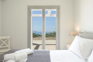 Ein Schlafzimmer mit Bett, Nachttisch, Lampe und Blick durch eine Schiebetür.
