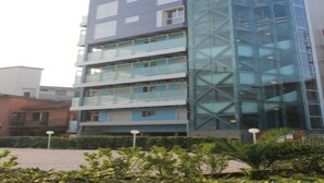 A multi-story building with a glass facade, balconies, and a courtyard with plants. - Vibrant Accommodation in Lignano Sabbiadoro (Lignano Sabbiadoro)