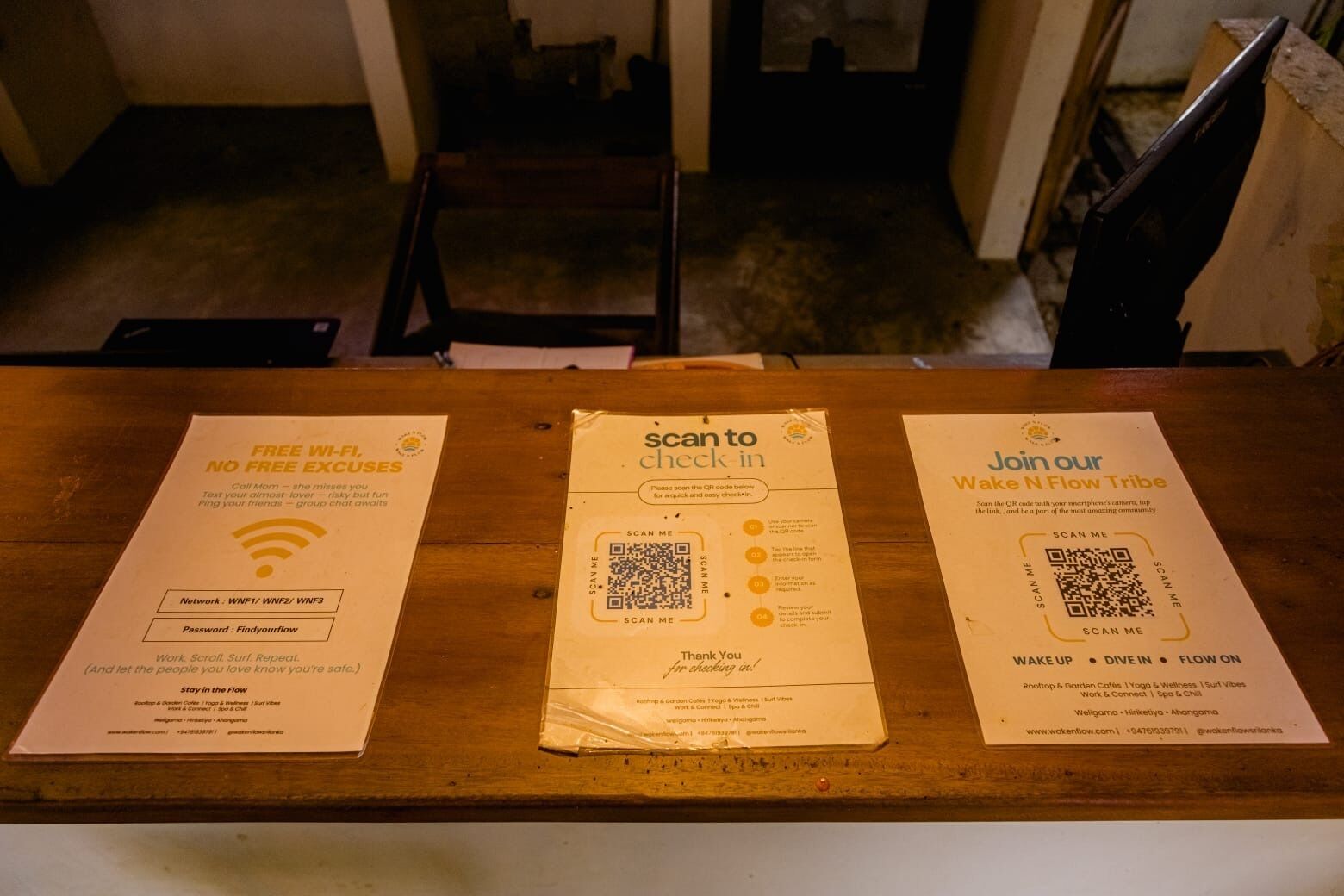 Three printed papers on a wooden table with QR codes and text.