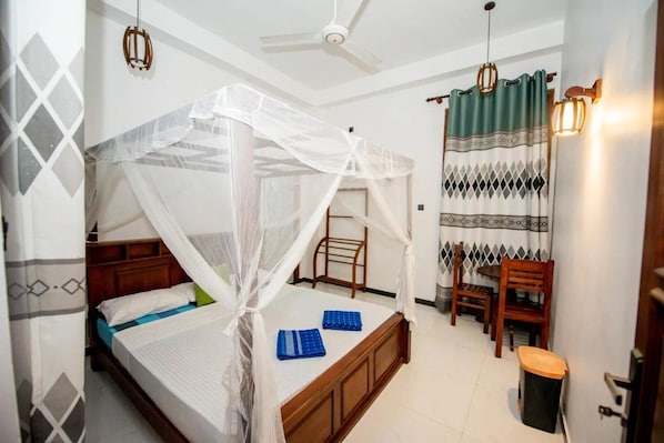 A bedroom with a four-poster bed, a chair, a small table, and a ceiling fan. - Wake N Flow, Hiriketiya (Hiriketiya)