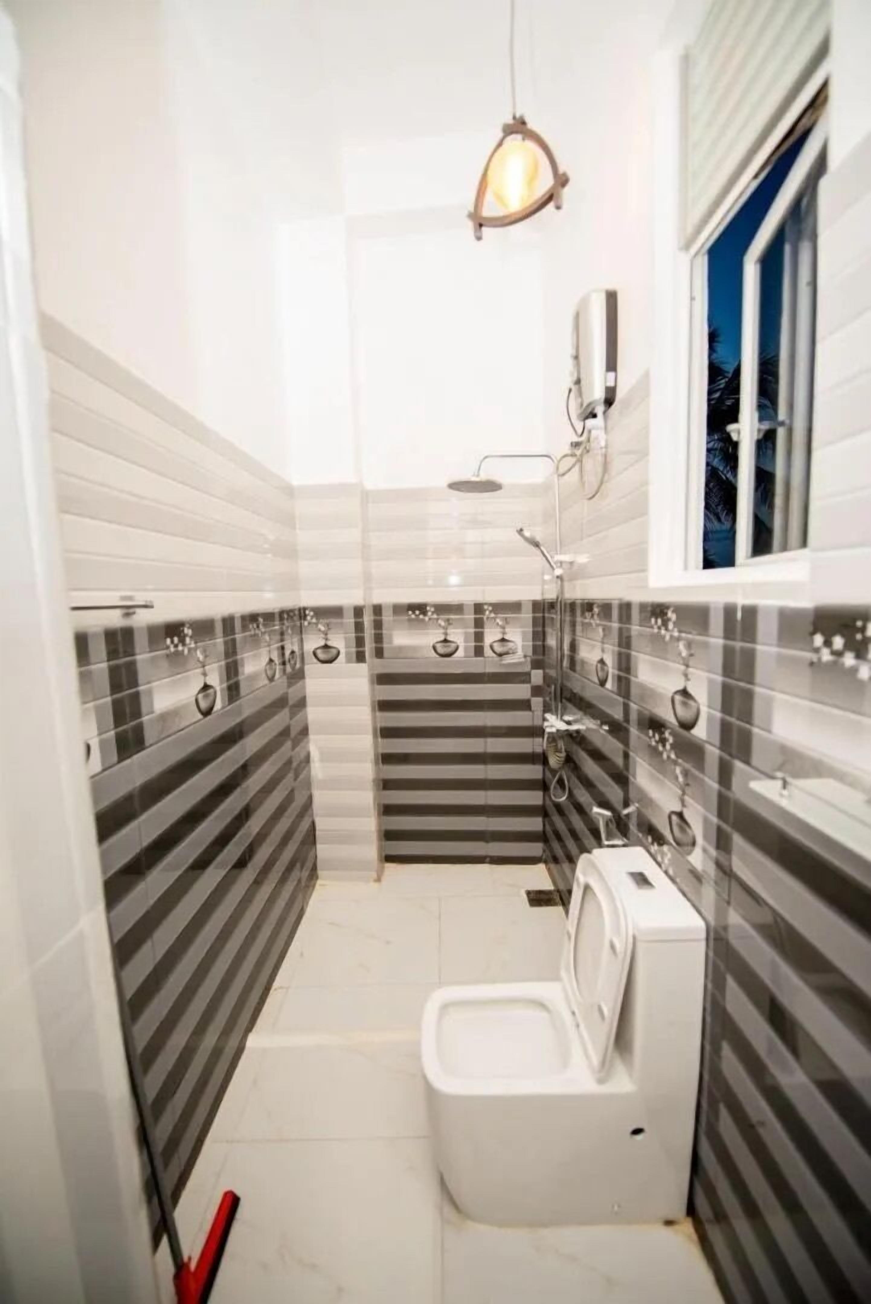 Un baño pequeño con ducha, inodoro y una ventana.