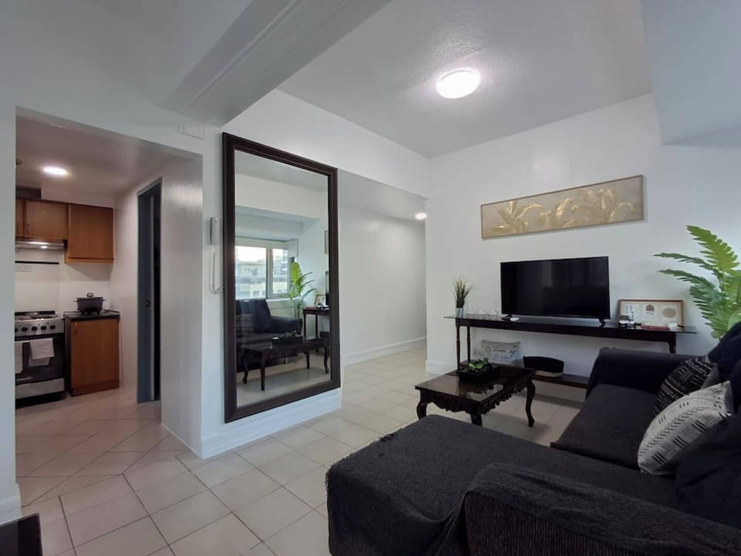 Una sala de estar moderna con un sofá, una mesa de centro, un televisor y un espejo grande.