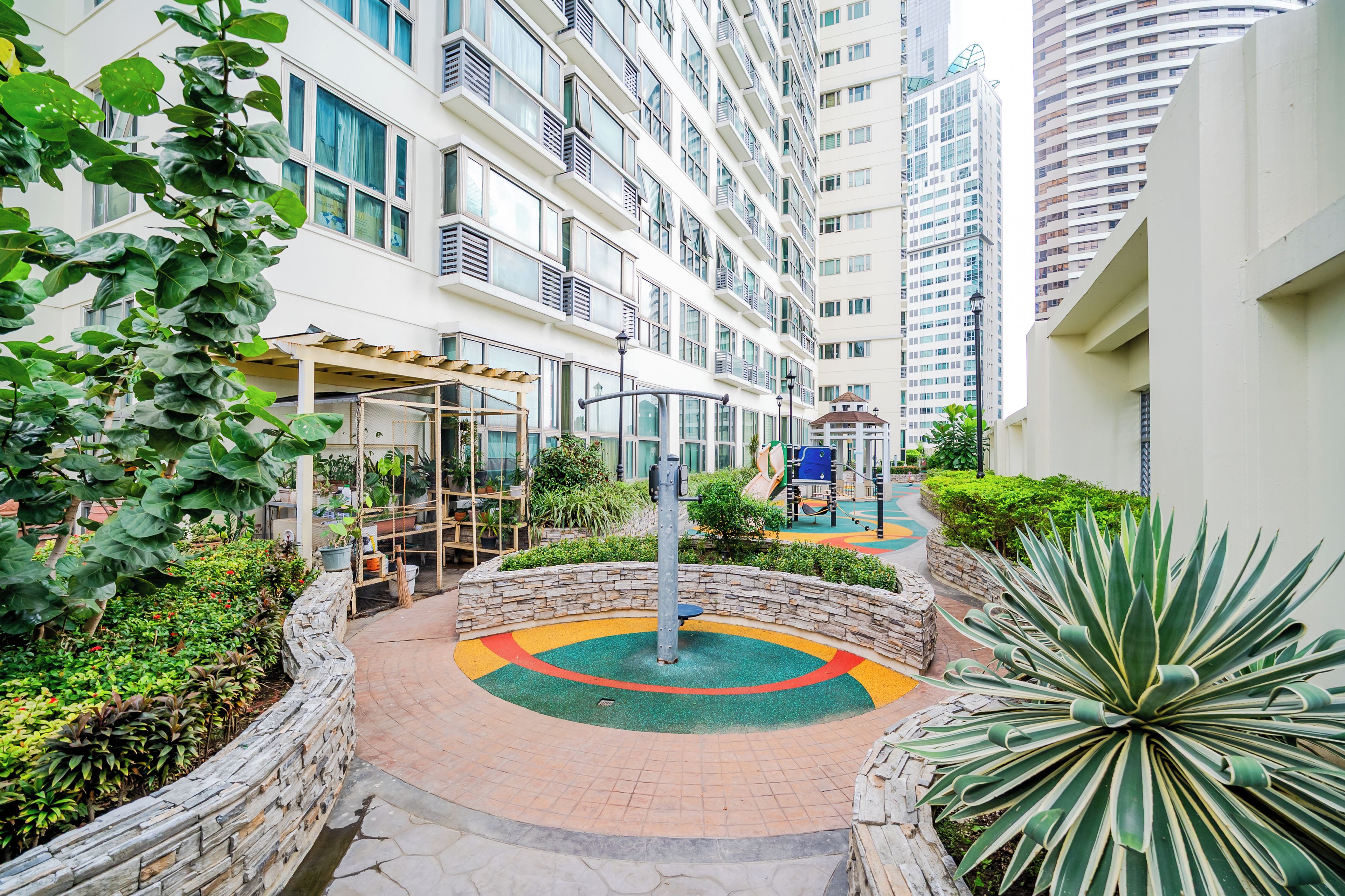 Un edificio residencial con varios pisos, balcones y un patio central con un área de juegos de colores.