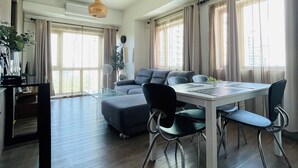 Una sala de estar moderna con comedor, ventanas amplias y ventilador de techo.