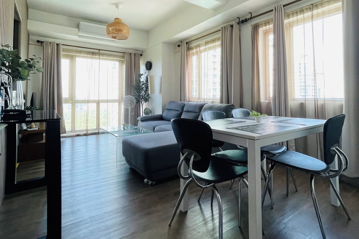 Una sala de estar moderna con comedor, ventanas amplias y ventilador de techo.