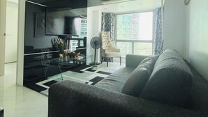 Una sala de estar moderna con sofá, televisor, ventilador y ventana con cortinas.