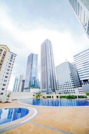 A modern urban setting with high-rise buildings, a swimming pool, and a clear sky. - Forbeswood Parklane (Taguig)