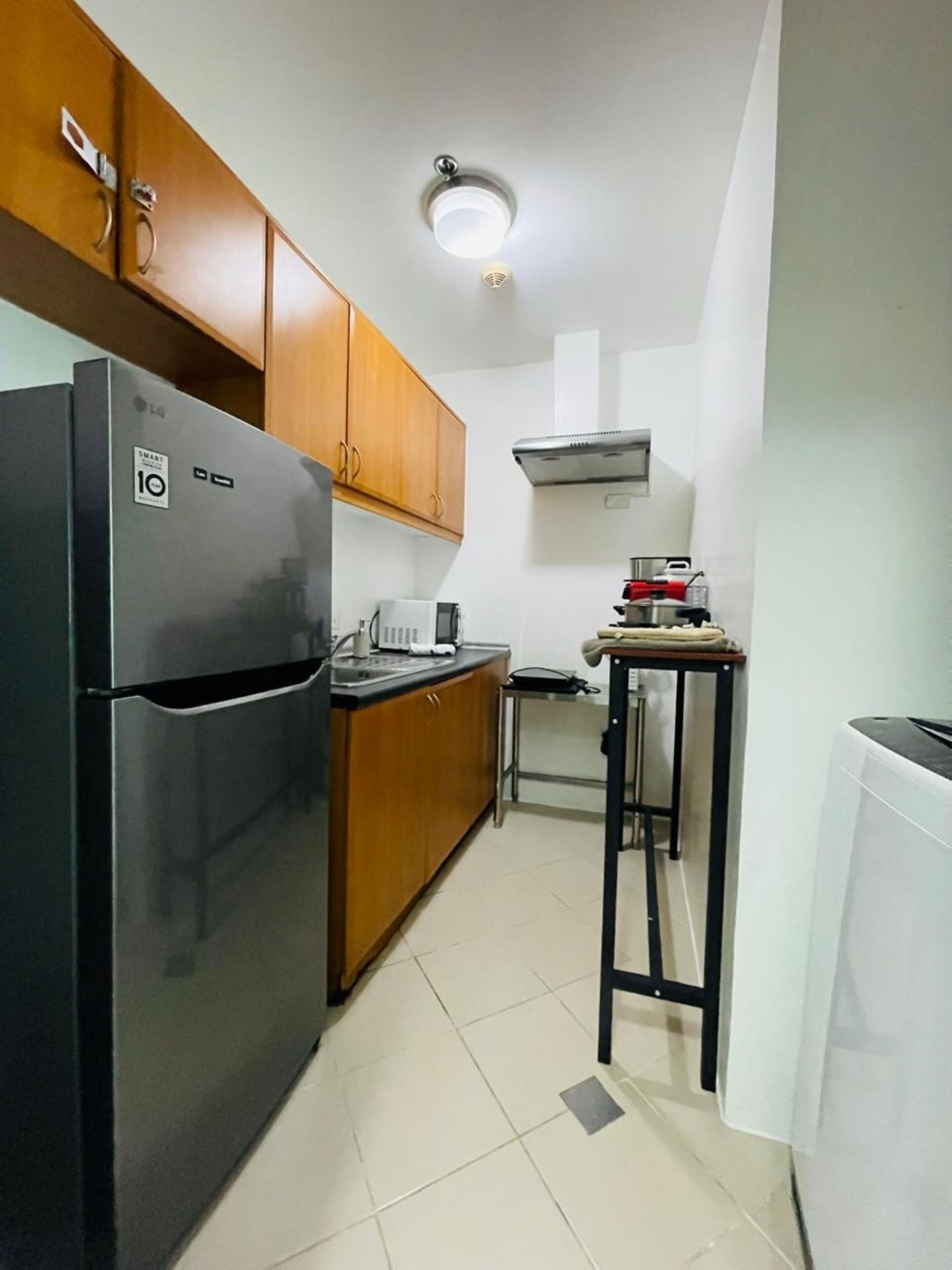 A compact kitchen with a black refrigerator, wooden cabinets, a small table, and a white radiator.