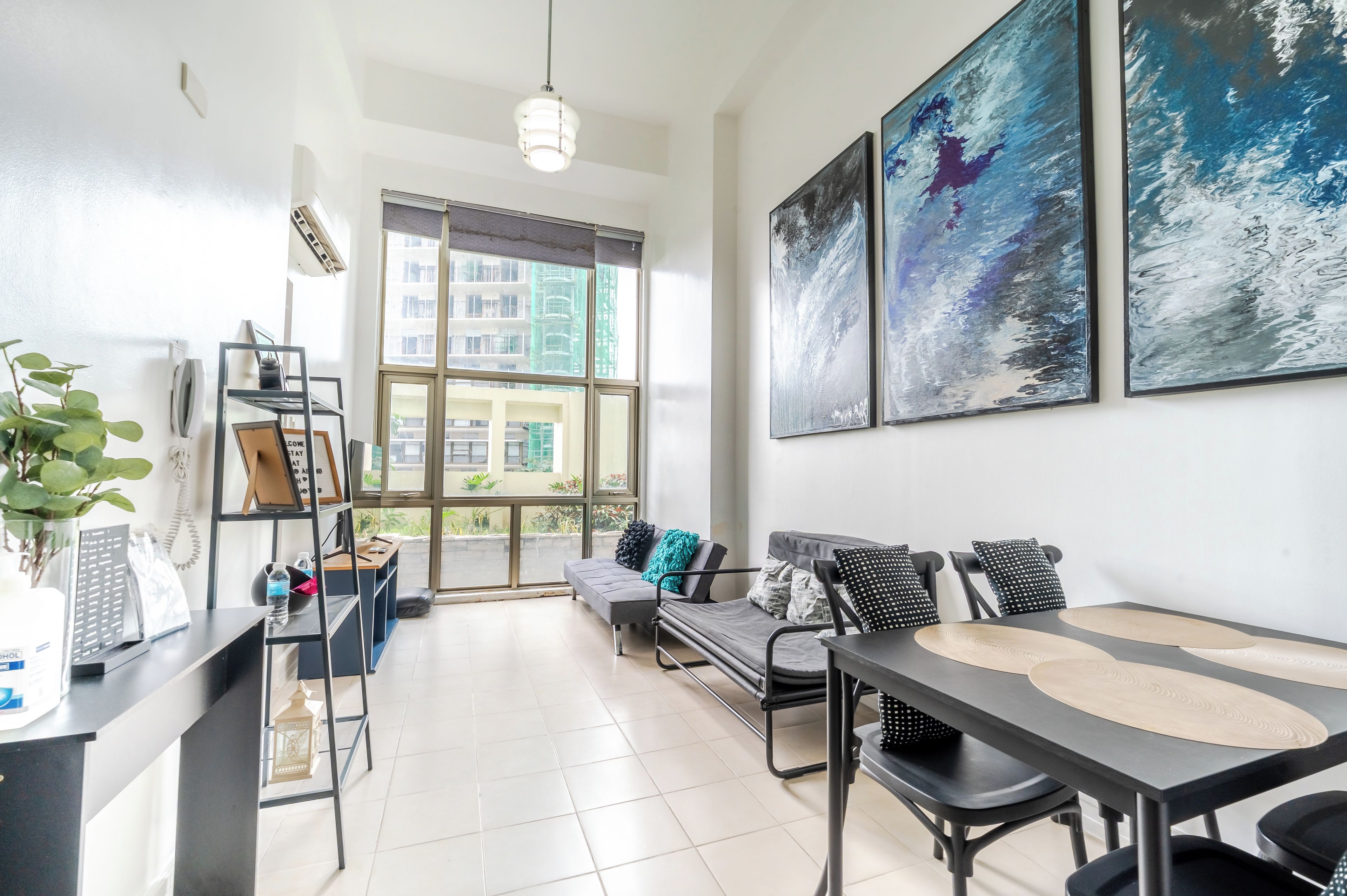 A modern living room with a sofa, chairs, a dining table, and artwork on the wall.