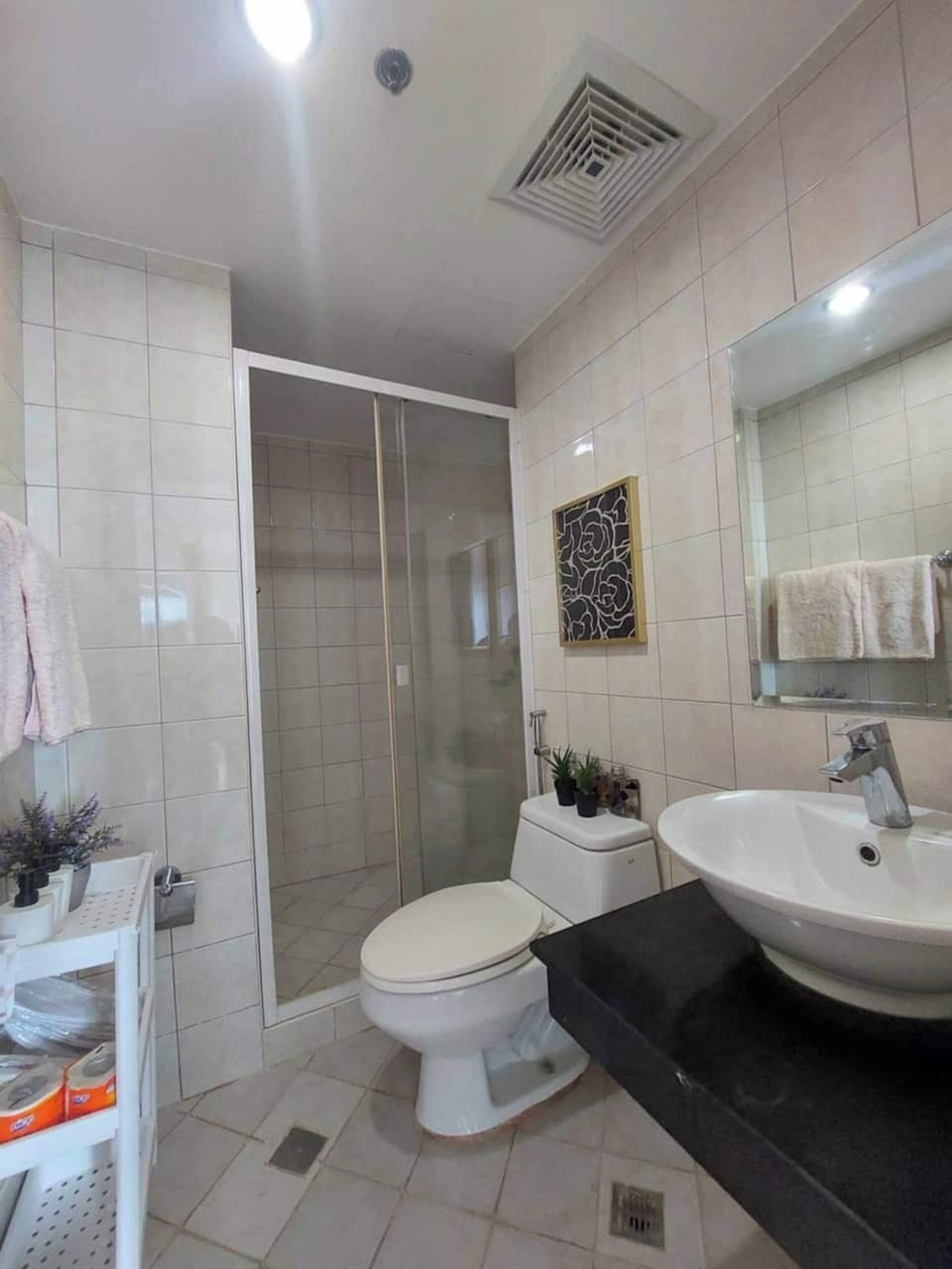 A modern bathroom with a shower, toilet, sink, and a large mirror.