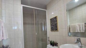 Un baño moderno con ducha, inodoro, lavamanos y un espejo grande.