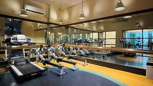 Un gimnasio con cintas de correr, elípticas y equipo de pesas.