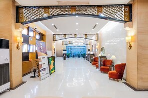 Un hall de hotel con mostrador de recepción, zona de estar y una araña.