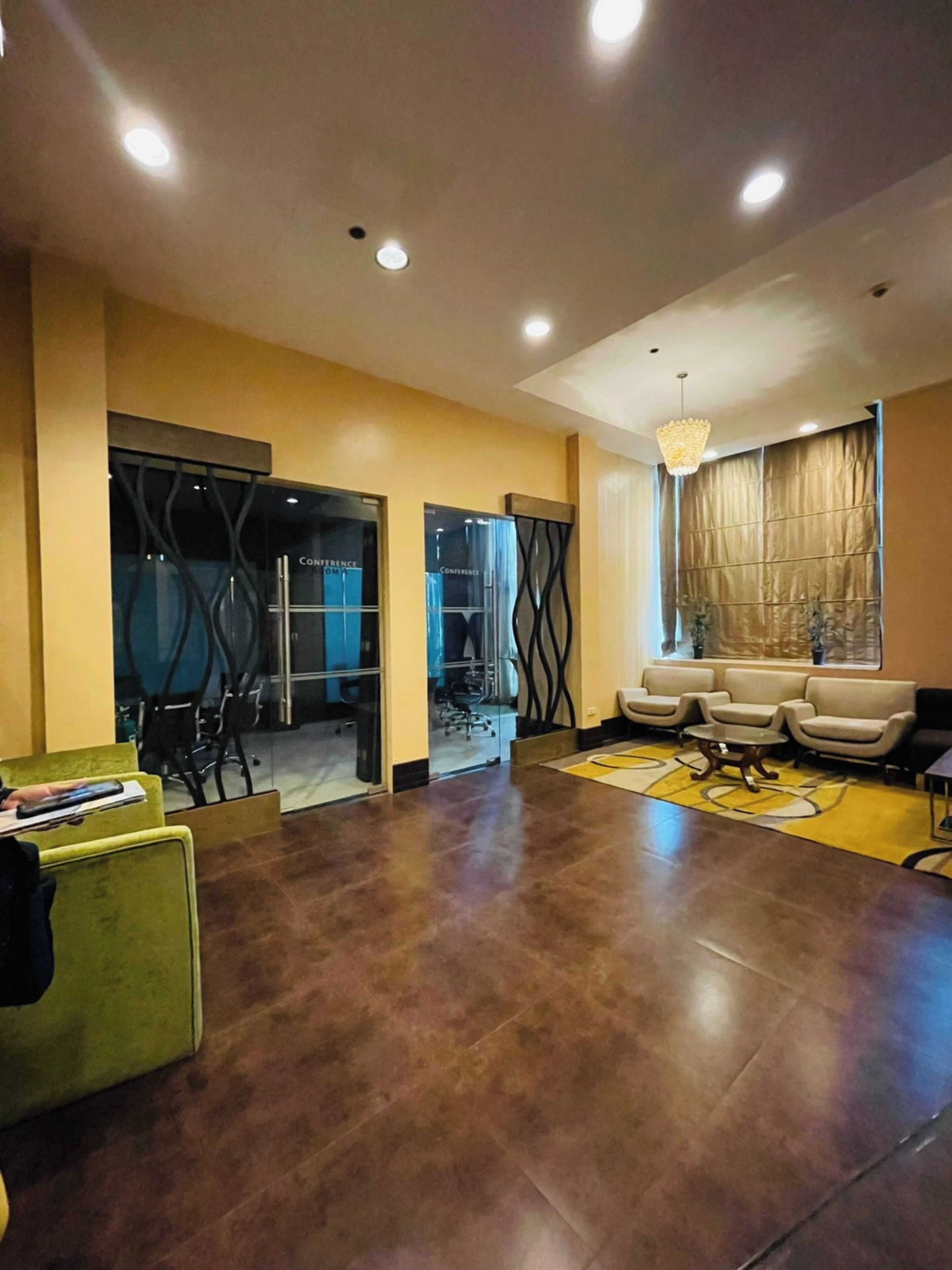 A modern lobby with a reception desk, seating area, and glass doors leading to a conference room.