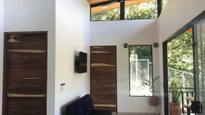 Un intérieur moderne agrémenté d’un ventilateur de plafond, de portes en bois, d’un banc et de grandes fenêtres offrant une vue sur la verdure.