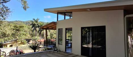 A modern house with a patio, a dining table, and a view of the surrounding landscape.