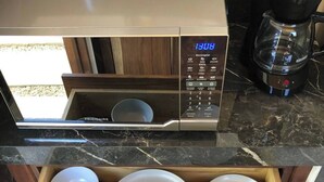 Une cuisine équipée d’un four à micro-ondes, d’une machine à café et d’un tiroir contenant des assiettes empilées.