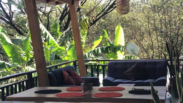 Un espace extérieur aménagé avec une table en bois, des chaises et des lampes suspendues.