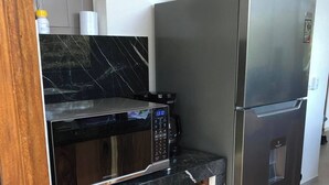 Une cuisine équipée d’un four à micro-ondes, d’un réfrigérateur et de meubles de rangement en bois.
