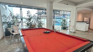 Ein Billardtisch in einem modernen Raum mit großen Fenstern und Blick auf Gebäude.