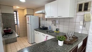 Eine Küche mit Granit Arbeitsplatten, weißen Schränken, einem Kühlschrank, einer Spüle und einem Telefon.