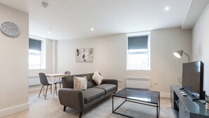 Uma sala de estar moderna com sofá, mesa de centro, TV e obras de arte na parede.