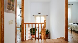 A staircase with wooden balusters, potted plants, a light switch, and a ceiling-mounted light fixture. - Casa Emilia: Rural Retreat with Private Terrace, Garden, and Wi-Fi (Baeza)