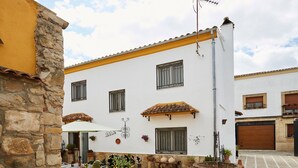 A courtyard with a white building, stone wall, and potted plants. - Casa Emilia: Rural Retreat with Private Terrace, Garden, and Wi-Fi (Baeza)