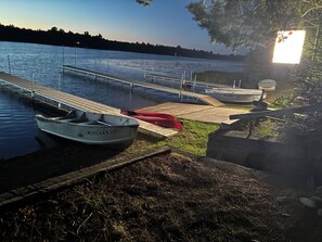 Ein ruhiger See mit angestaubten Booten, einer Holzsteganlage und einer Rasenfläche.