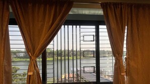 Una habitación con un ventanal grande con vistas al agua, un balcón y la vista de un puente.