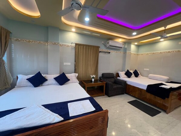 Een hotelkamer met twee bedden, een bank, een kleine tafel en een airconditioning.