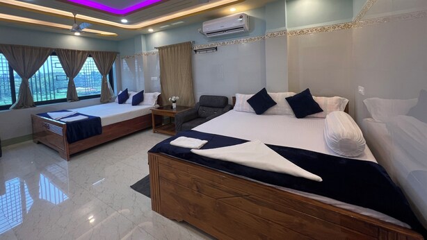 Habitación de hotel con dos camas, ventilador de techo, aire acondicionado y vistas al exterior.