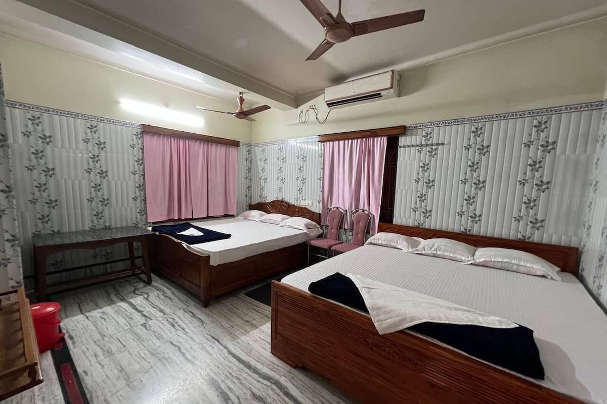 A hotel room with two wooden beds, a marble floor, a ceiling fan, an air conditioning unit, and floral-patterned curtains.