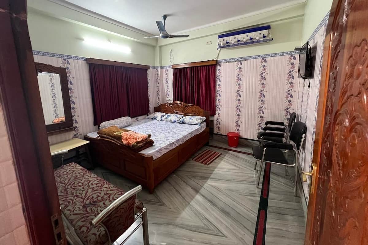 A bedroom with a bed, a desk, a chair, a wardrobe, and a ceiling fan.