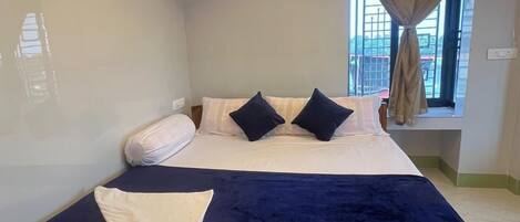 Un dormitorio con cama, aire acondicionado, ventana con cortinas y vistas al exterior.