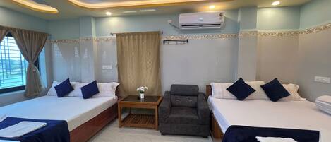 A hotel room with two beds, a desk, a chair, an air conditioner, and a window with curtains.
