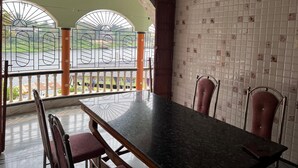 Un comedor con mesa y sillas, vista a través de una puerta de vidrio y pared de azulejos.