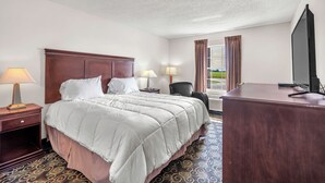 Una habitación de hotel con una cama grande, dos lámparas de noche, un escritorio con computadora y una ventana con cortinas.