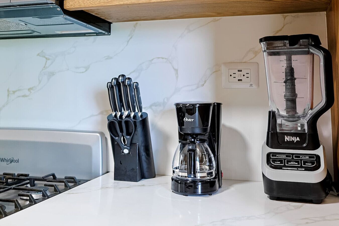A kitchen with a Whirlpool stove, a Oster coffee maker, and a Ninja blender.