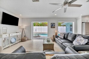 Ein modernes Wohnzimmer mit einer Couch, einem Couchtisch, einem Fernseher und einem Deckenventilator.
