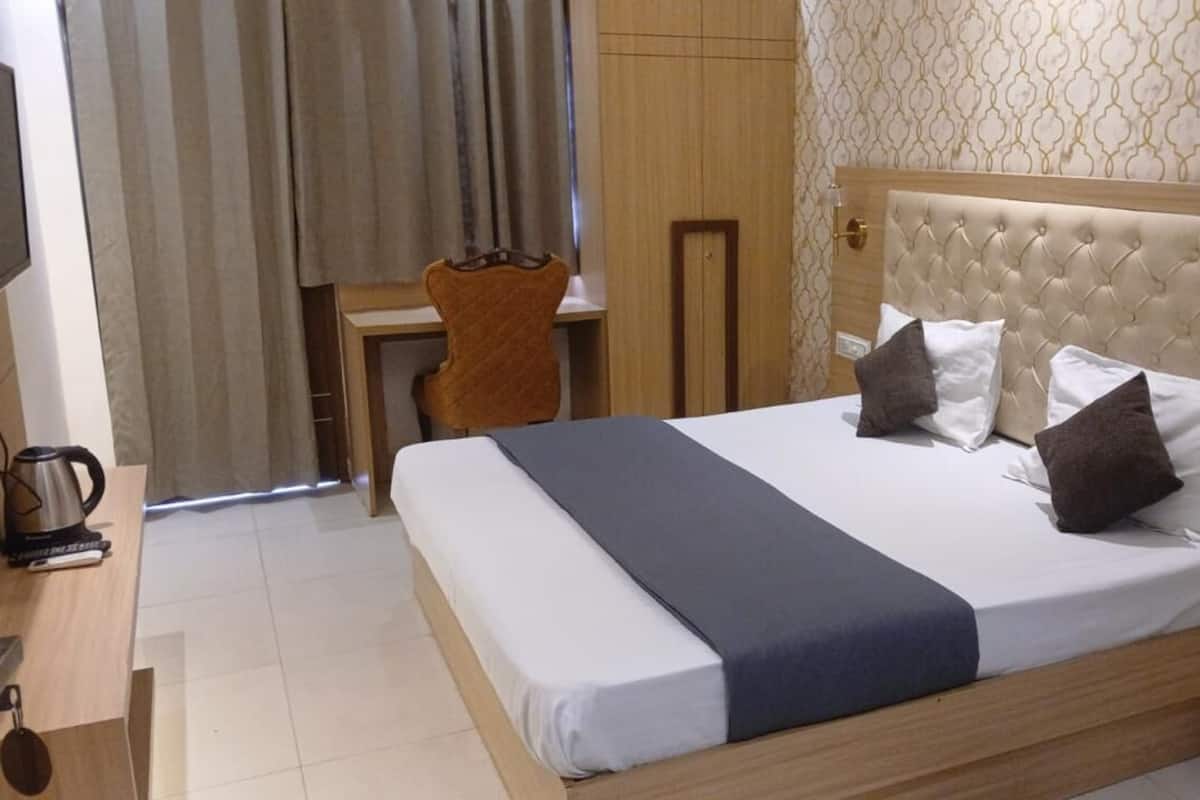 Una habitación de hotel con cama, mesita de noche, escritorio y silla.