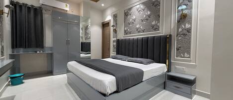 A modern bedroom with a large bed, wardrobe, and a vanity with a mirror.