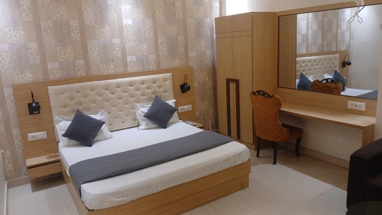 Een slaapkamer met een bed, een bureau, een stoel, een kledingkast en een spiegel.
