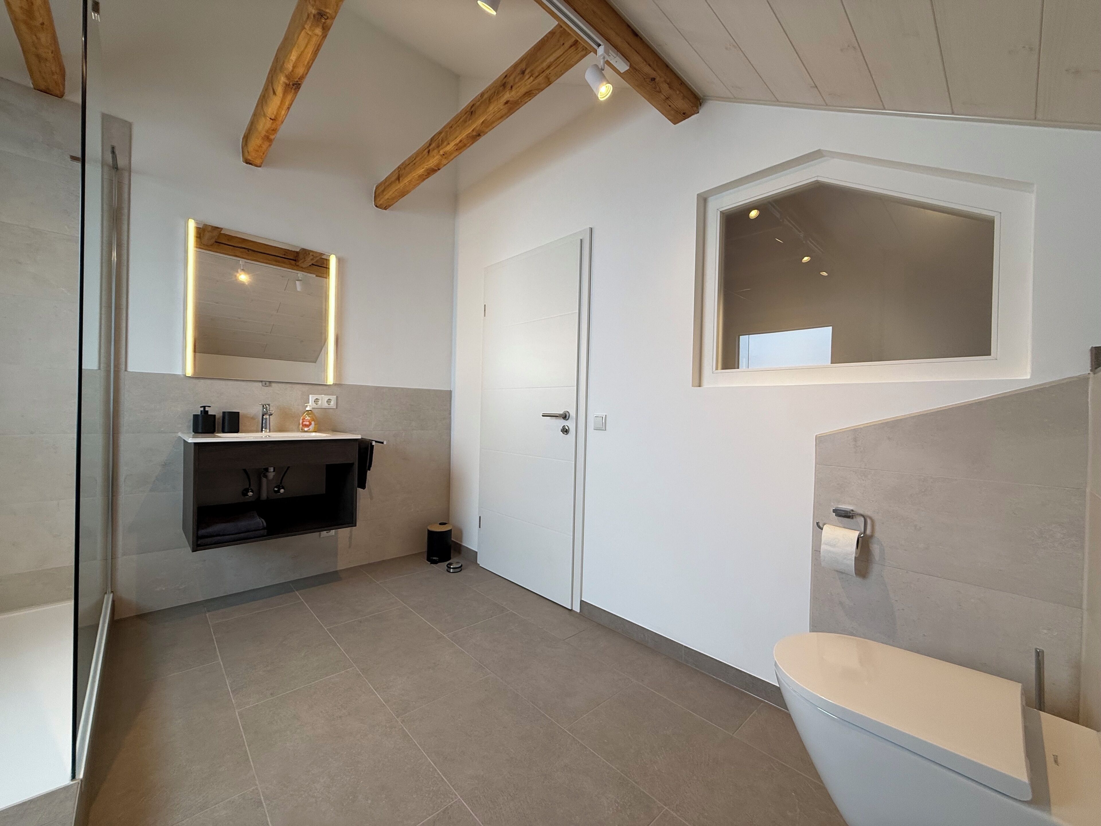 A modern bathroom with a toilet, sink, and mirror.