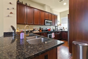 A kitchen with granite countertops, stainless steel appliances, wooden cabinets, and a stainless steel sink. - Pool, Hot Tub, 3 bedrooms 3 bathrooms walkable cute neighborhood near downtown. (Houston)
